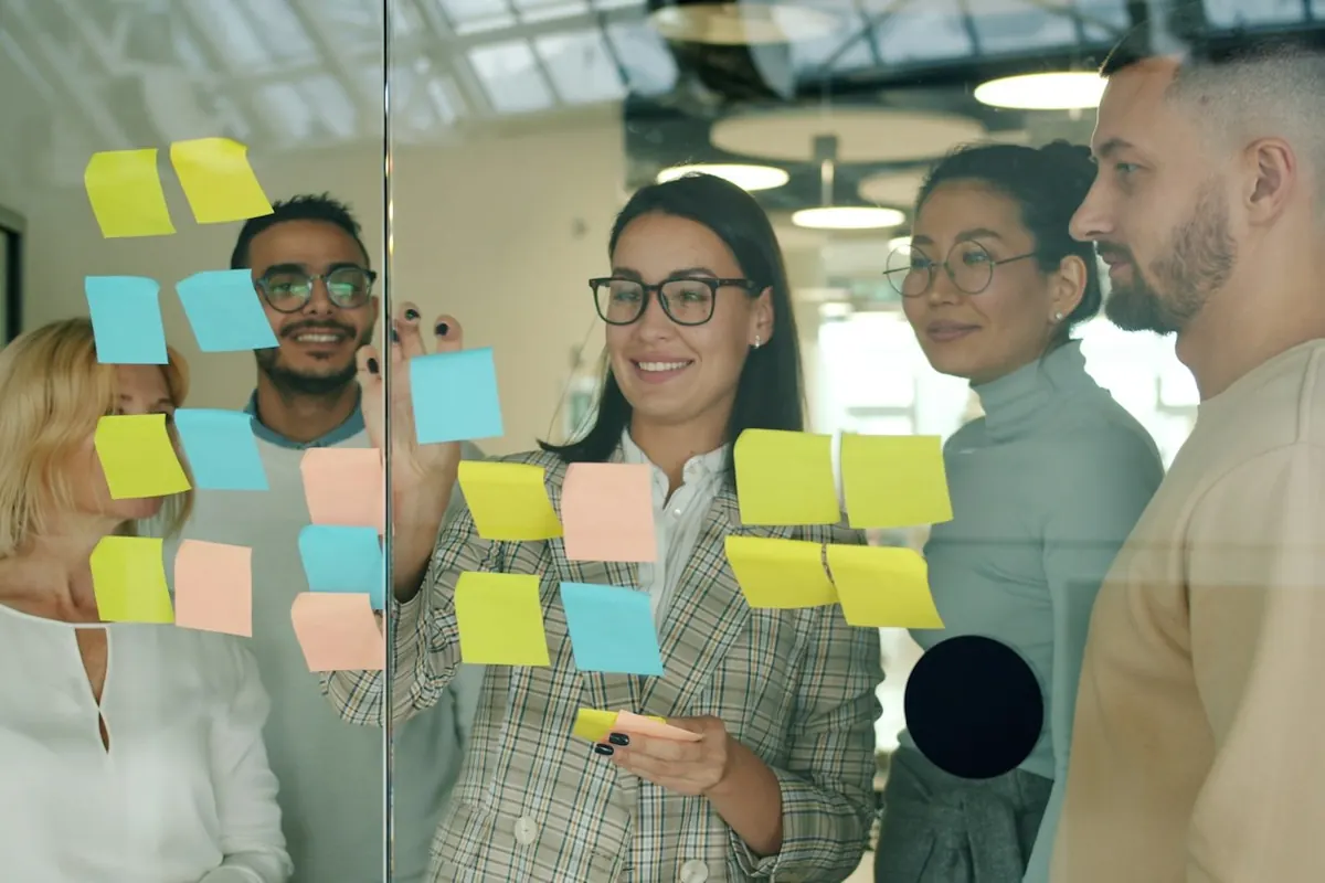 Team collaborating with sticky notes on glass wall