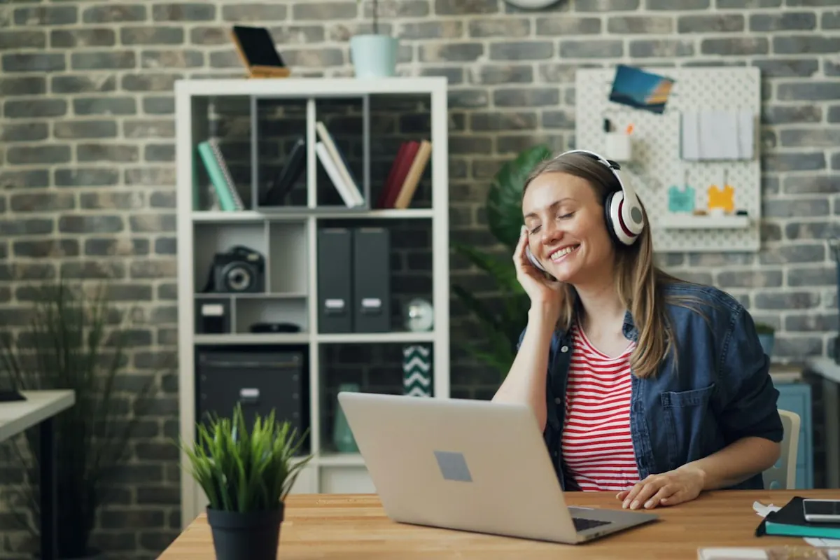 a woman sitting in front of a laptop computer wearing headphones