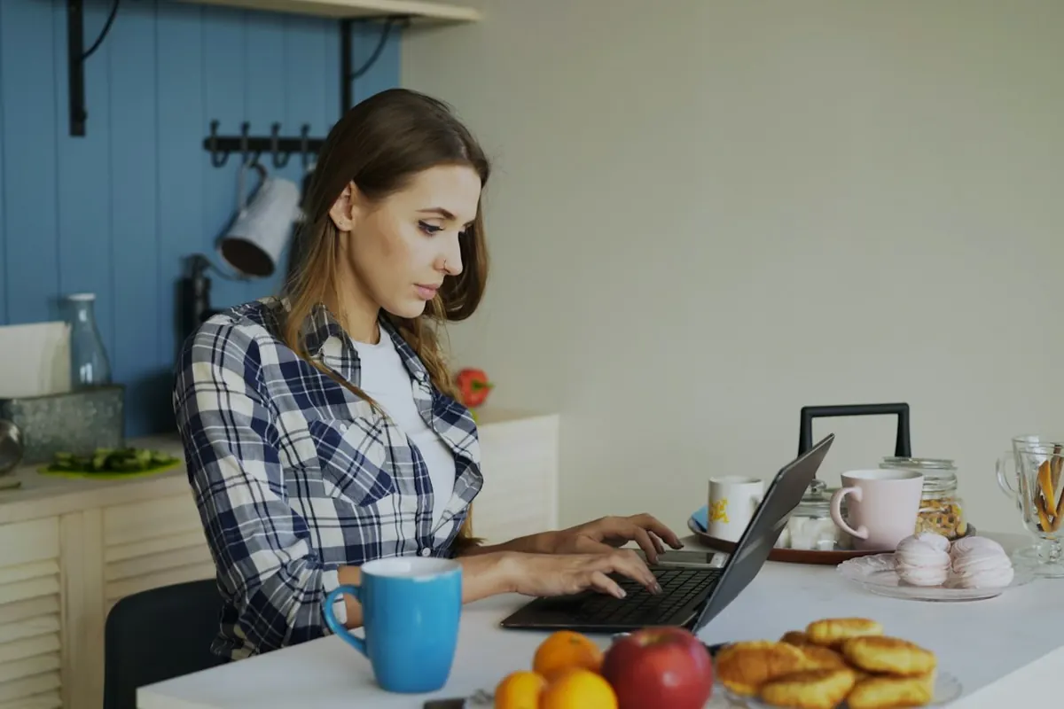 Woman working on laptop in a bright kitchen