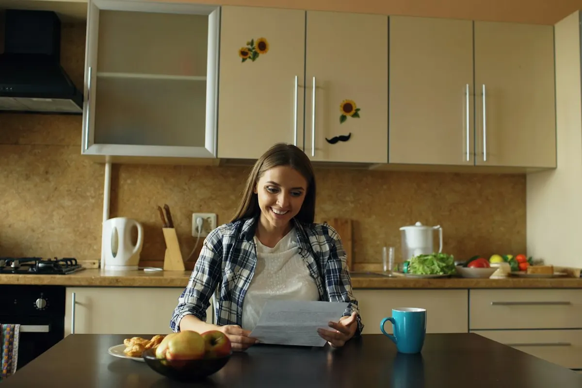 Woman reading document at kitchen table with coffee